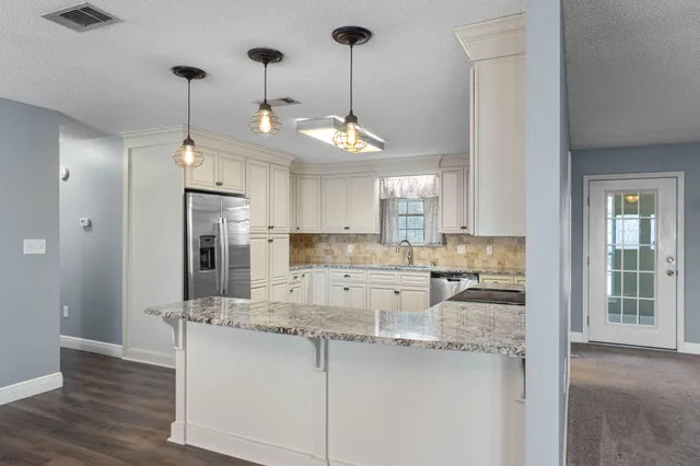 a kitchen with stainless steel appliances granite countertop a sink a refrigerator a stove a microwave and island