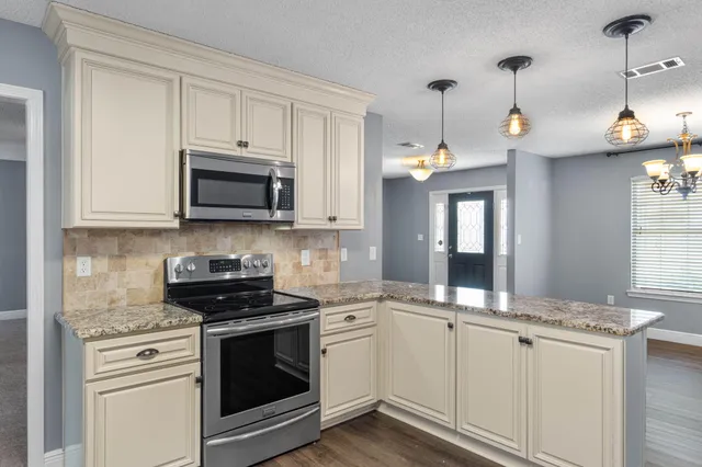 a kitchen with granite countertop white cabinets white stainless steel appliances and a sink