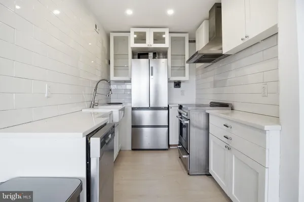 a kitchen with stainless steel appliances kitchen island a refrigerator sink and cabinets