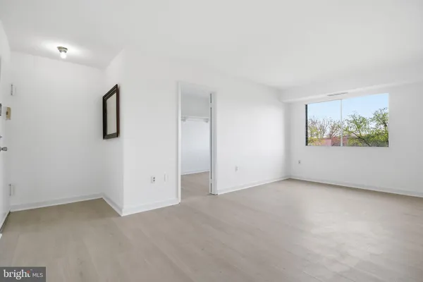 an empty room with windows and refrigerator