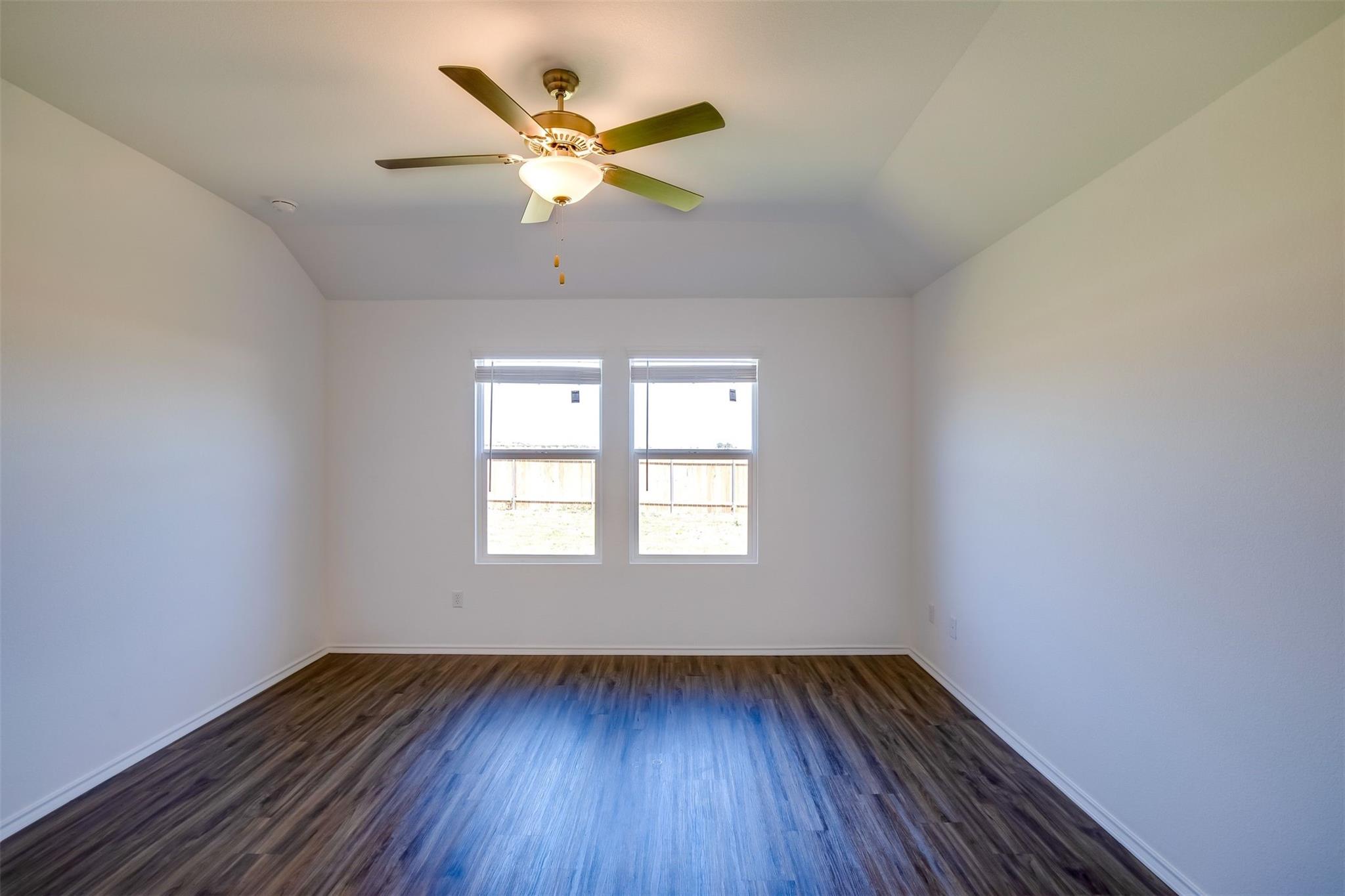614 Milliner Loop Hutto, TX 78634 - Photo 13 of 25 A well-lit bedroom features vaulted ceilings and rich wood flooring.
