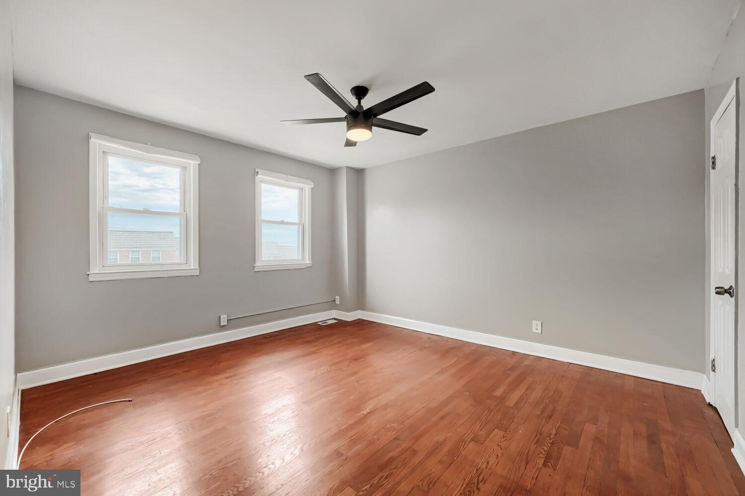 1014 Lyndhurst Street Baltimore, MD 21229 - Photo 18 of 29 an empty room with wooden floor ceiling fan and windows