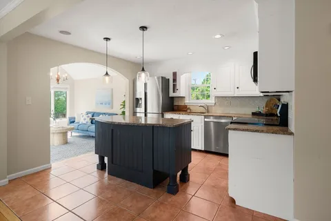 a kitchen with stainless steel appliances granite countertop a refrigerator a sink dishwasher and a wooden cabinets