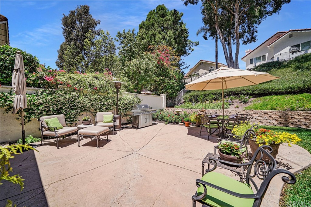 19 Springbrook Road Laguna Niguel, CA 92677 - Photo 28 of 41 a view of a patio with chairs and a table and chairs under an umbrella with potted plants