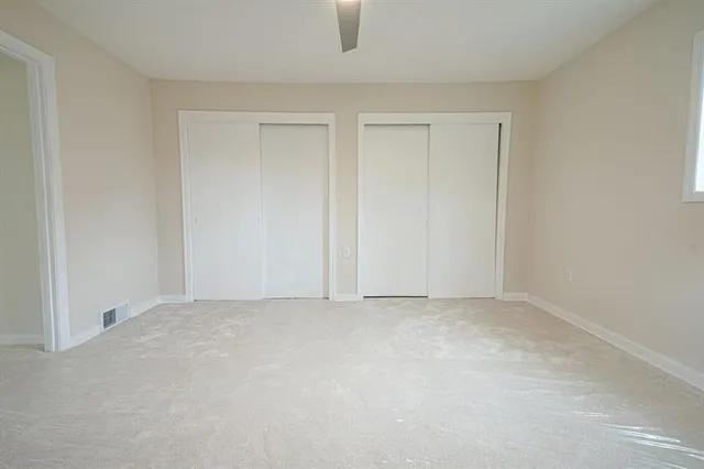 an empty room with a ceiling fan and a window