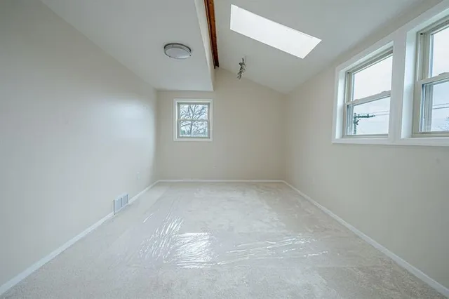 a view of an empty room with window and closet area