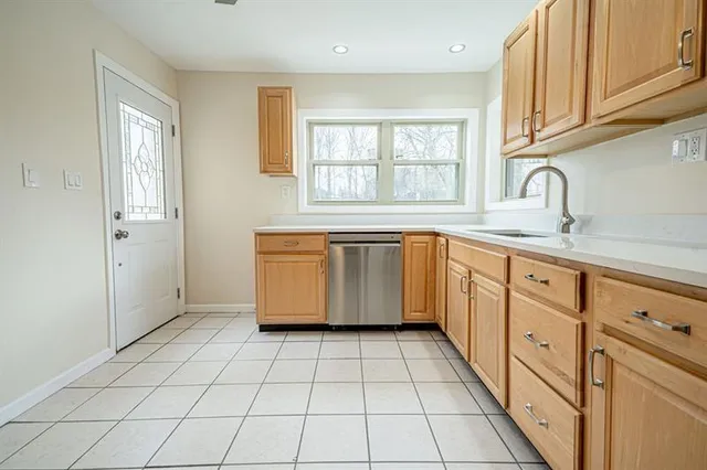 a kitchen with white cabinets appliances and a window