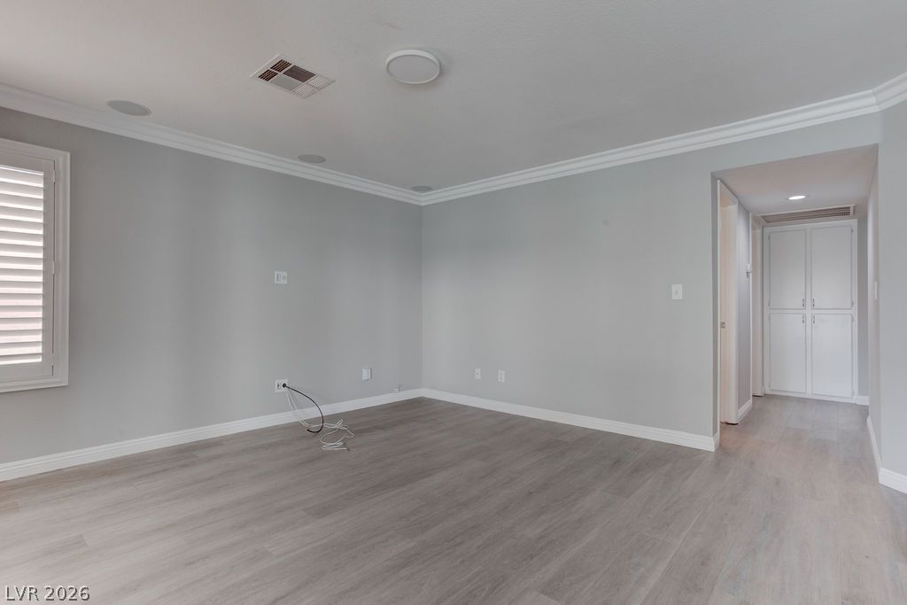 1416 Walstone Road North Las Vegas, NV 89031 - Photo 14 of 47 Refined wood-look flooring graces this versatile room, accented by elegant crown molding and recessed lighting.