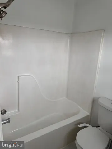 a white toilet sitting next to a bath tub and a shower