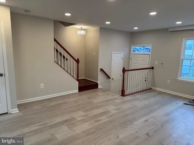 a view of an empty room with wooden floor and windows