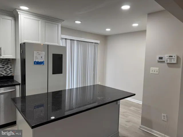 a kitchen with stainless steel appliances granite countertop a refrigerator a stove and a sink with wooden floor