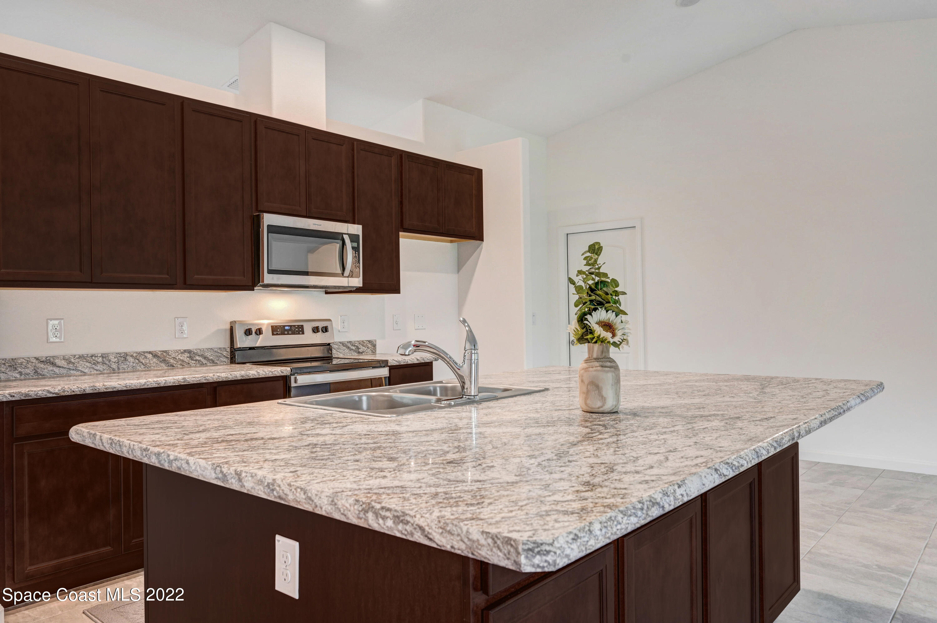 561 Scenic Road Palm Bay, FL 32908 - Photo 16 of 40 a kitchen with granite countertop a stove a sink and a microwave