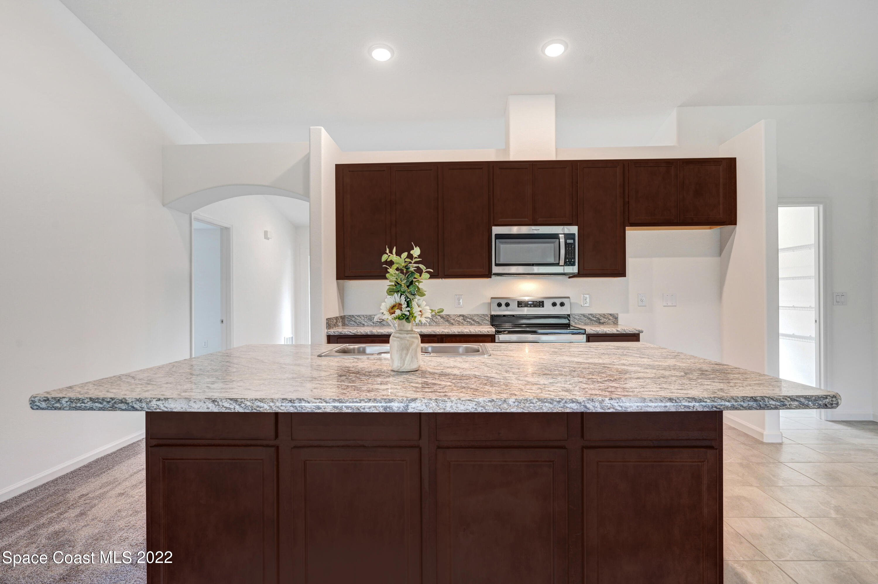 561 Scenic Road Palm Bay, FL 32908 - Photo 17 of 40 a kitchen with stainless steel appliances granite countertop a sink a stove and a microwave