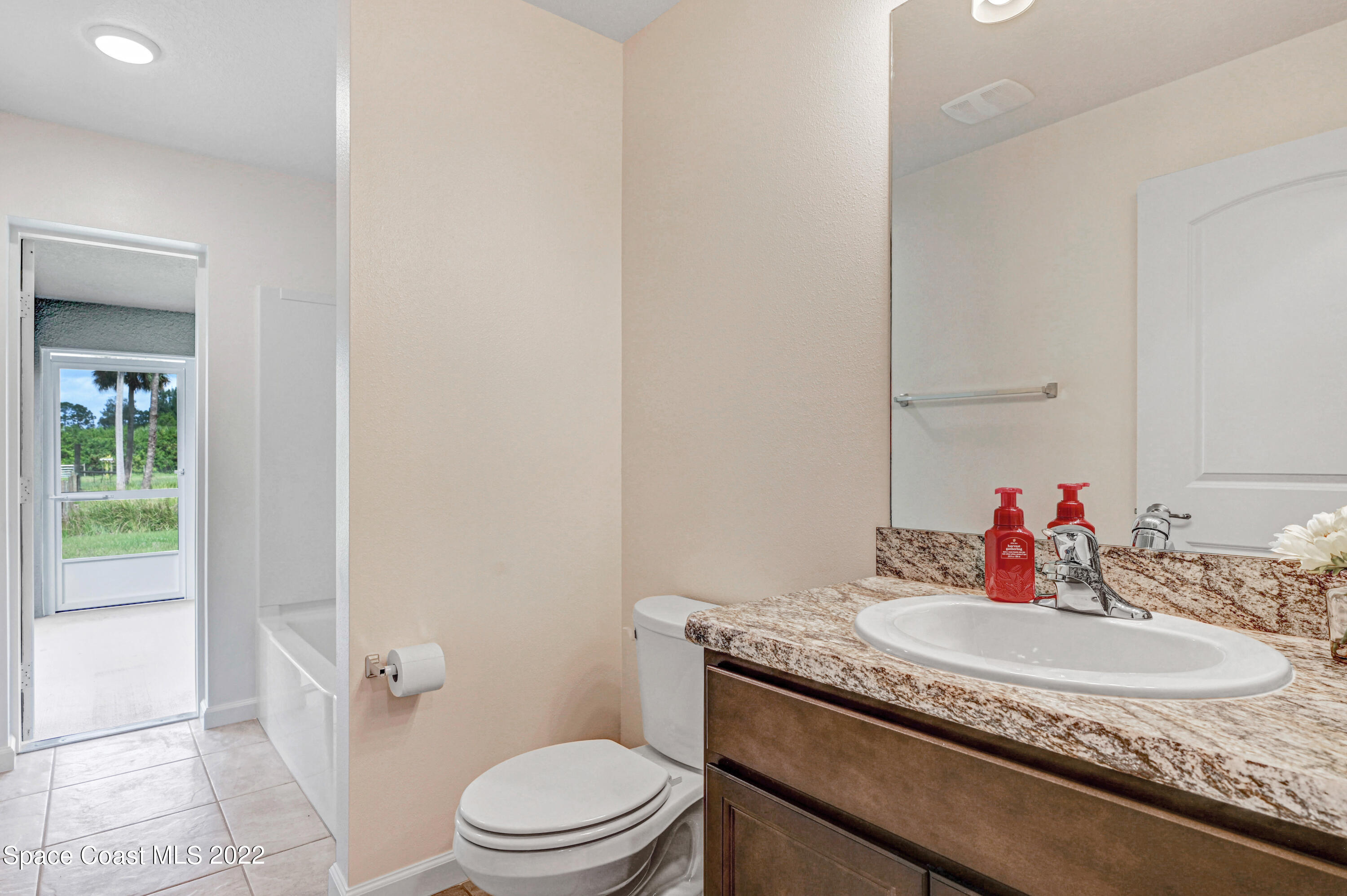 561 Scenic Road Palm Bay, FL 32908 - Photo 37 of 40 a bathroom with a granite countertop sink a toilet and a mirror
