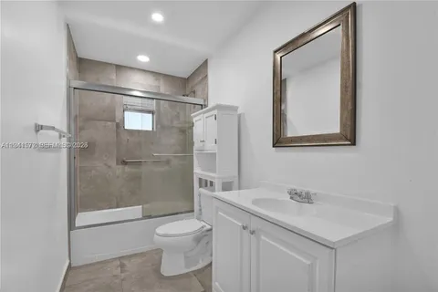 a bathroom with a shower sink vanity mirror and toilet
