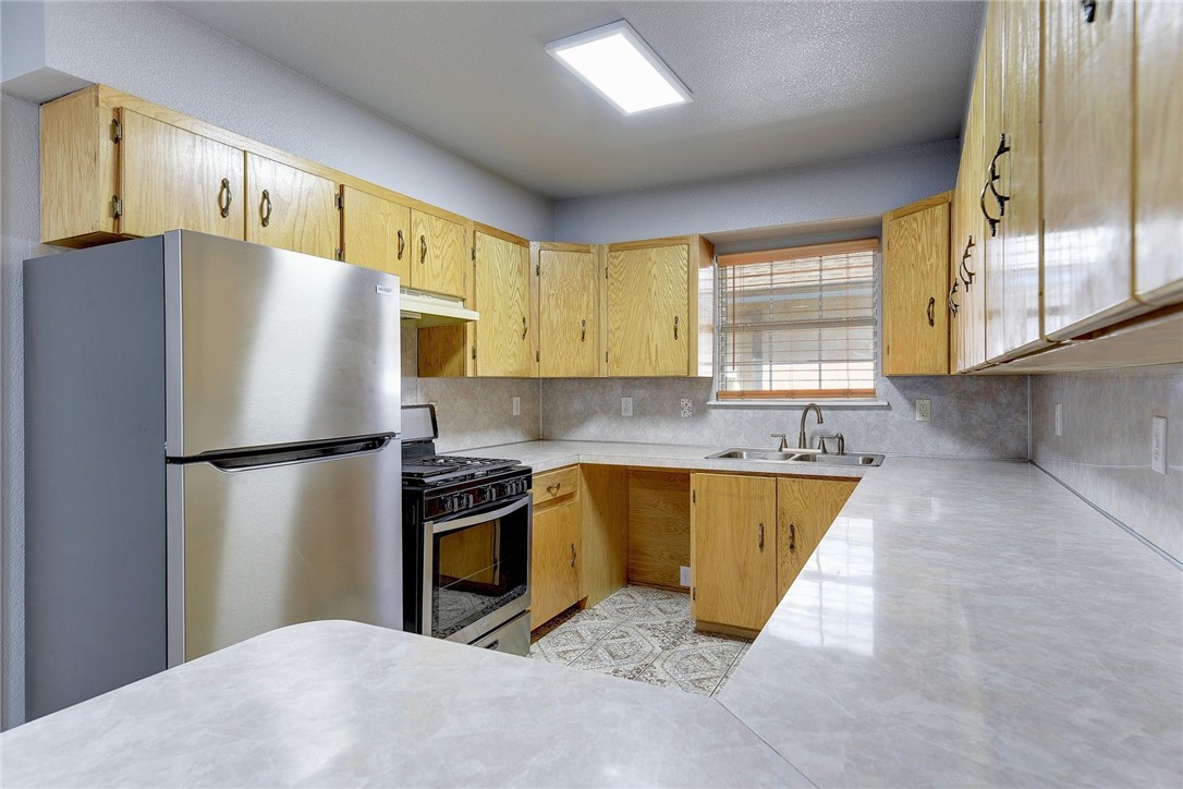 6402 Santos Street Austin, TX 78741 - Photo 12 of 22 a kitchen with stainless steel appliances granite countertop a refrigerator a sink dishwasher a stove with wooden cabinets