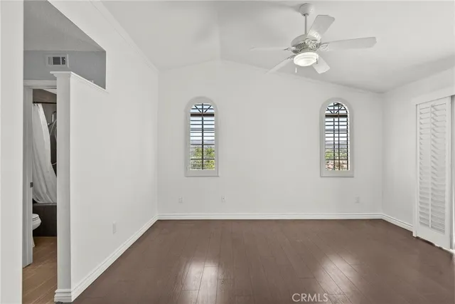 an empty room with wooden floor closet and windows