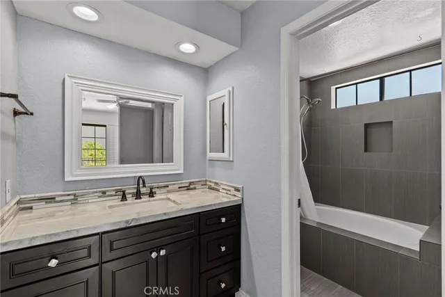 a bathroom with a granite countertop sink a mirror and a shower