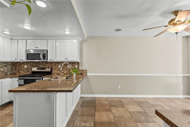 a kitchen with kitchen island granite countertop a sink and a stove top oven