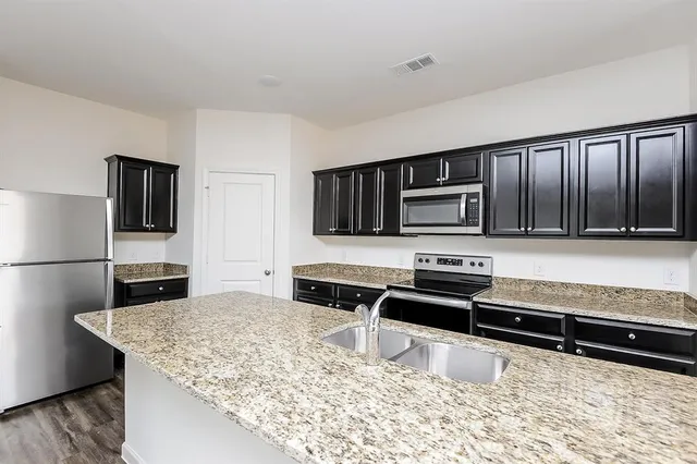 a kitchen with stainless steel appliances granite countertop a stove microwave and refrigerator