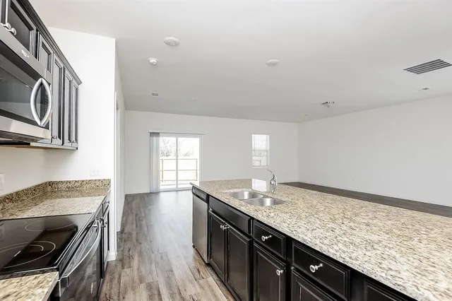 a kitchen with granite countertop stainless steel appliances sink stove top oven and cabinets