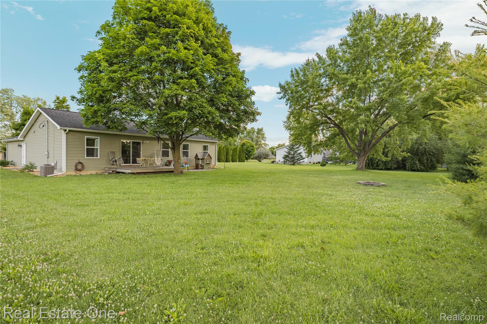 Expansive green lawn with mature trees and a rear deck