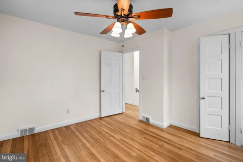 a view of a room with wooden floor and a ceiling fan