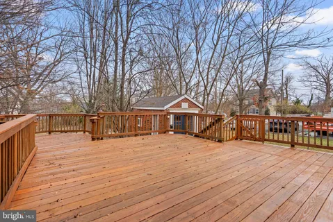 a view of house with wooden deck and trees