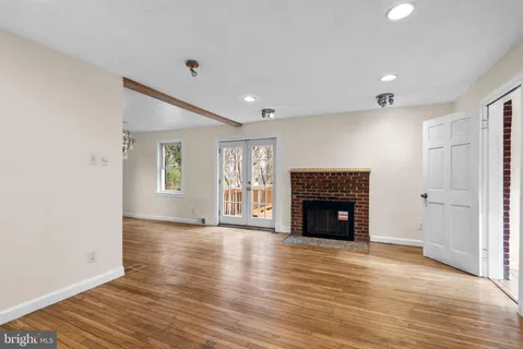 an empty room with wooden floor fireplace and windows