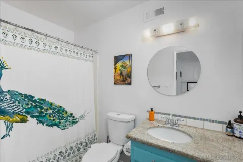 a bathroom with a granite countertop toilet sink and mirror
