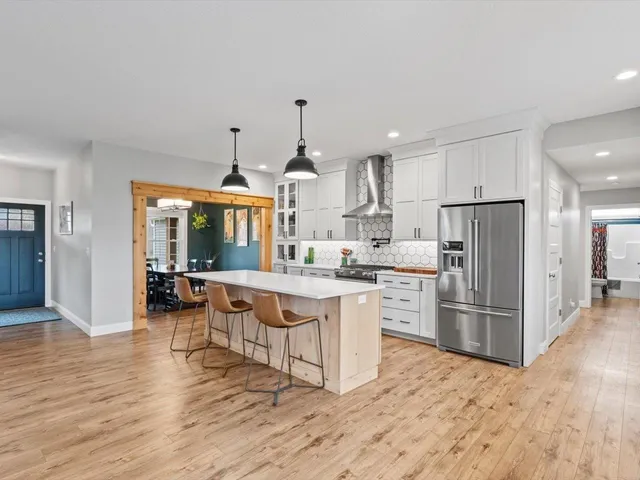 a kitchen with stainless steel appliances granite countertop a refrigerator a stove top oven and a sink