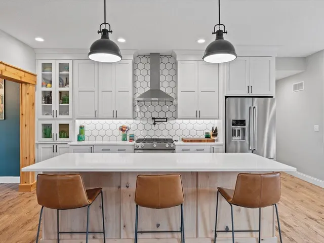a kitchen with stainless steel appliances granite countertop a dining table chairs and white cabinets