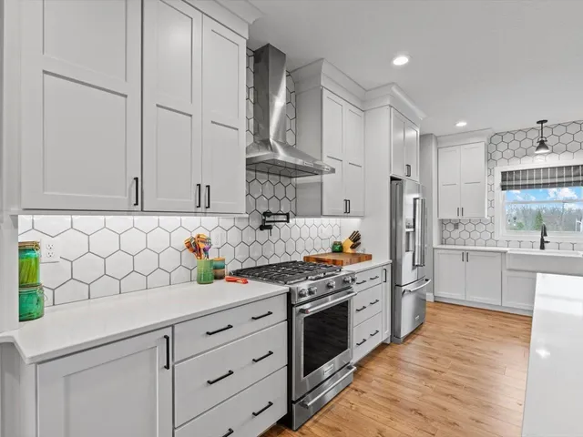 a kitchen with stainless steel appliances a stove and white cabinets