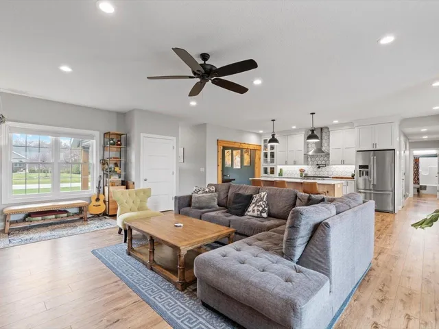 a living room with furniture and a large window with kitchen view