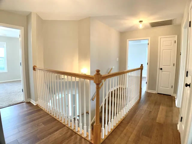 a view of an empty room with wooden floor and a ceiling fan