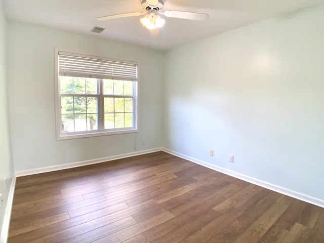 an empty room with windows and fan