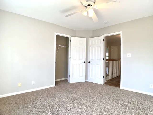 an empty room with wooden floor and a ceiling fan