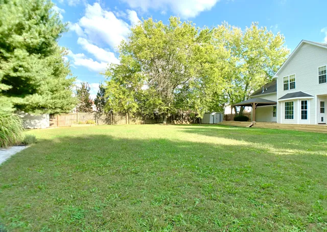 a view of a house with a yard and a large tree
