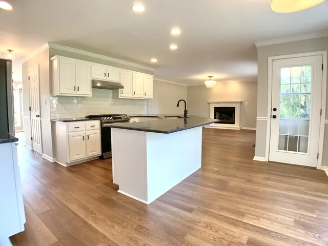 a kitchen with granite countertop a sink cabinets and wooden floor
