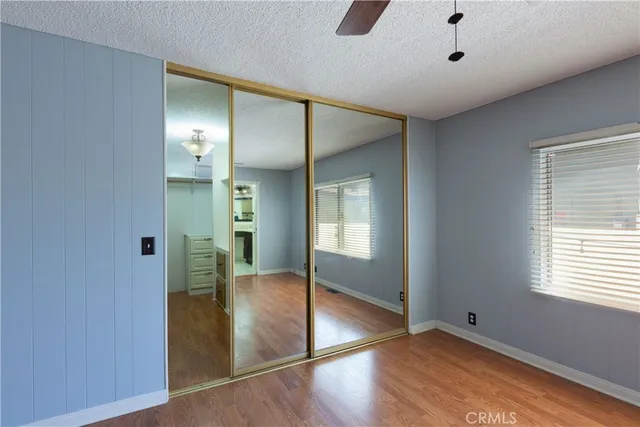 a view of empty room with wooden floor and fan