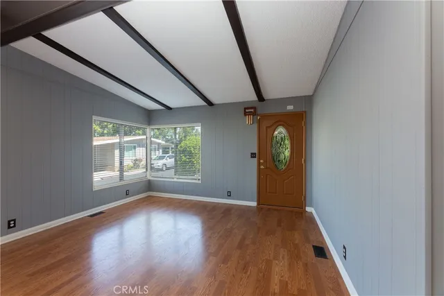 a view of an empty room with wooden floor and windows