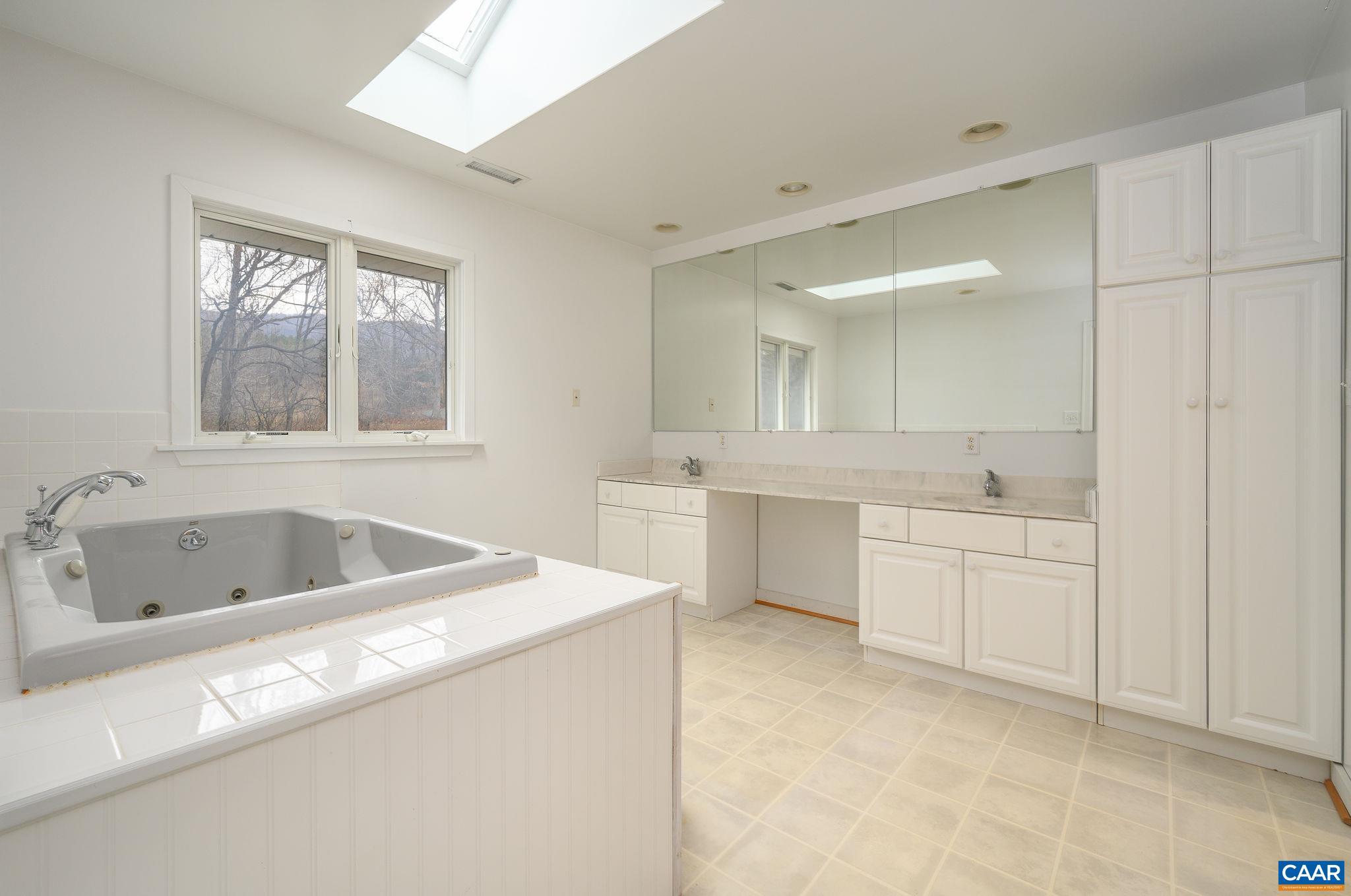 9165 Dick Woods Road Afton, VA 22920 - Photo 29 of 56 a bathroom with a granite countertop sink mirror bathtub and window