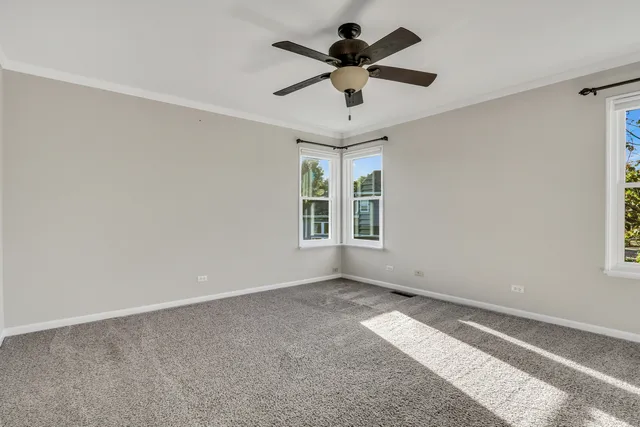 an empty room with a ceiling fan and windows