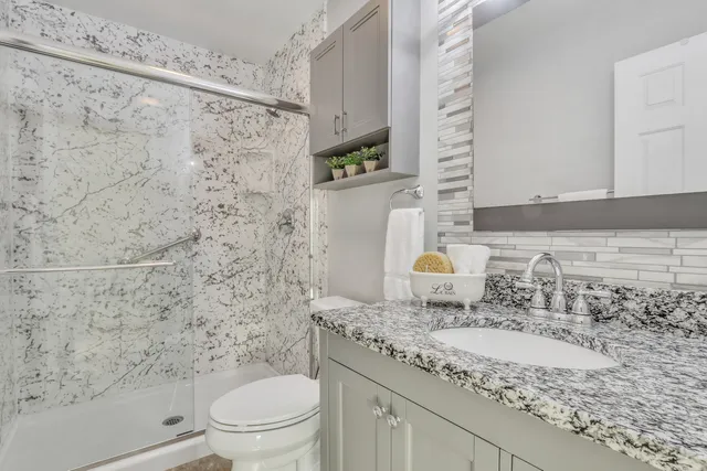 a bathroom with a granite countertop sink a toilet and shower