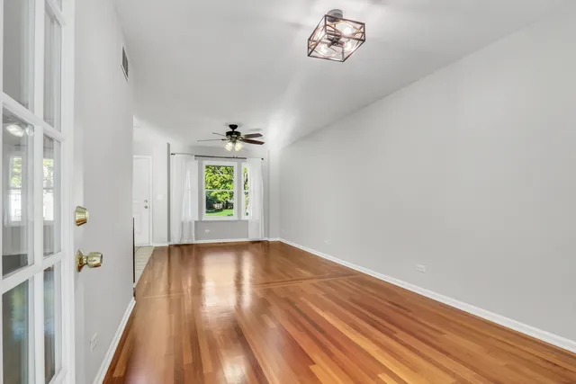 a view of an empty room with a window and wooden floor