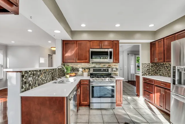 a kitchen with stainless steel appliances a stove a sink a microwave a refrigerator and cabinets