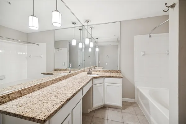 a bathroom with a granite countertop bathtub a sink and a shower