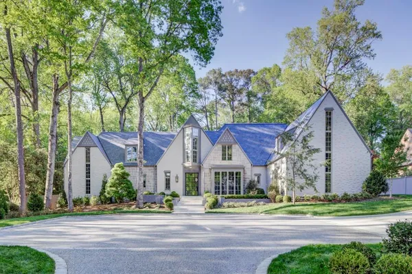 front view of house with a yard and large trees