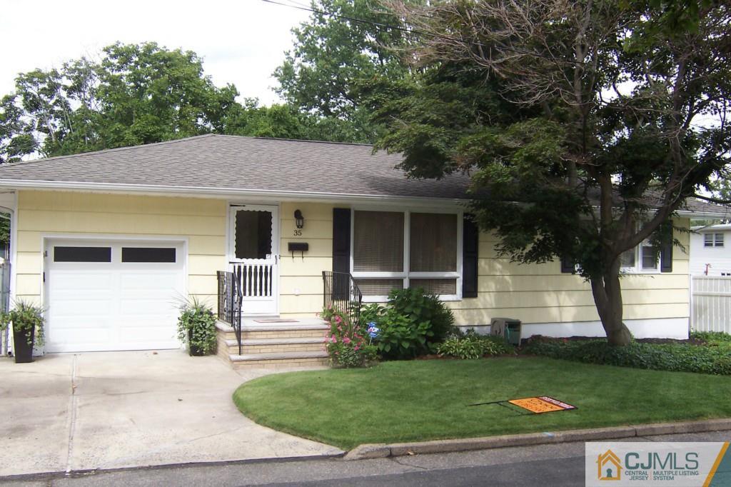 a front view of a house with a garden and a tree