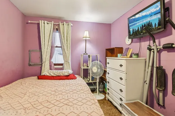 a bedroom with a bed and a flat tv screen on dresser